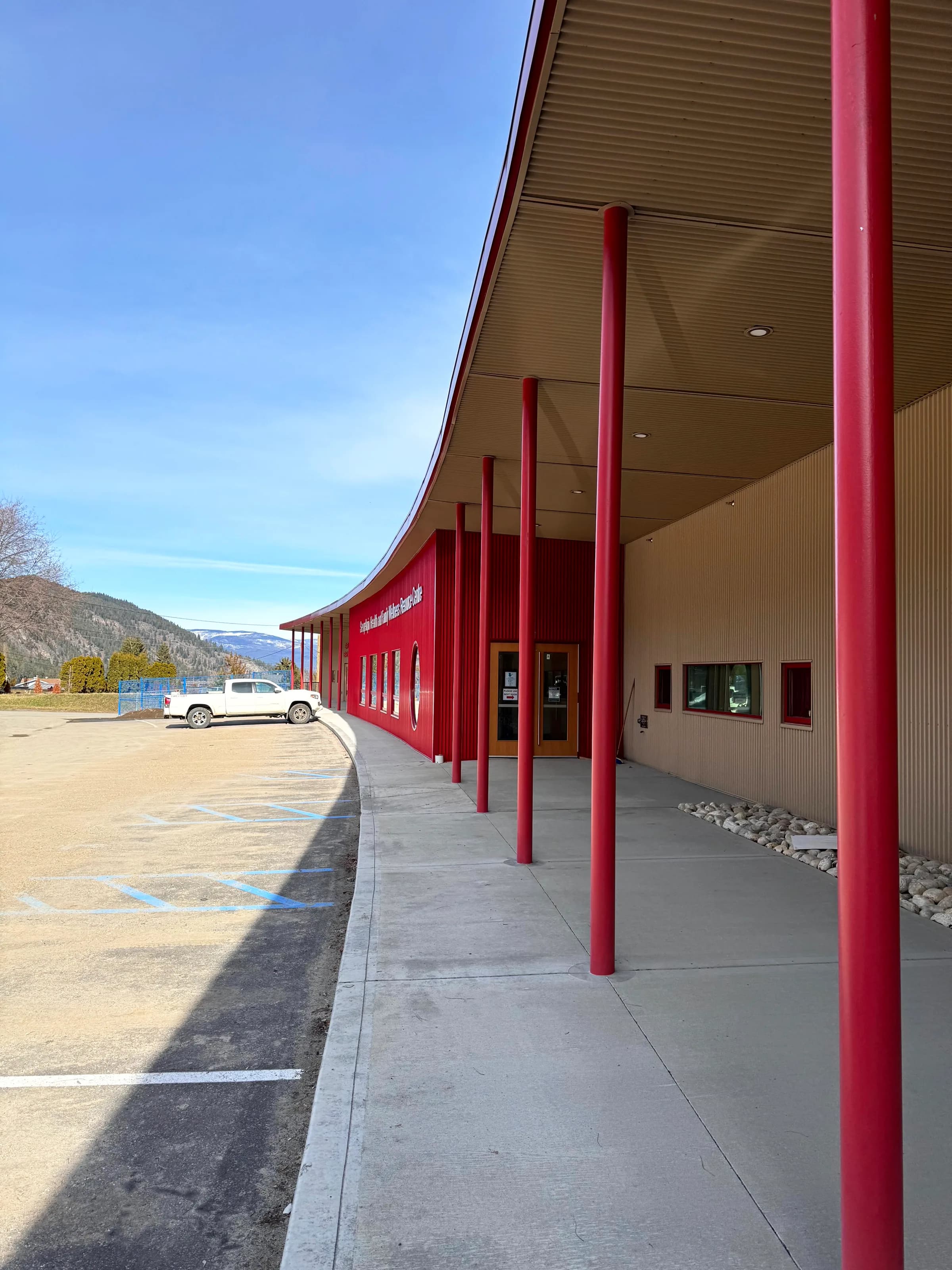 The covered walkway along the front of the building, carried on red steel columns.