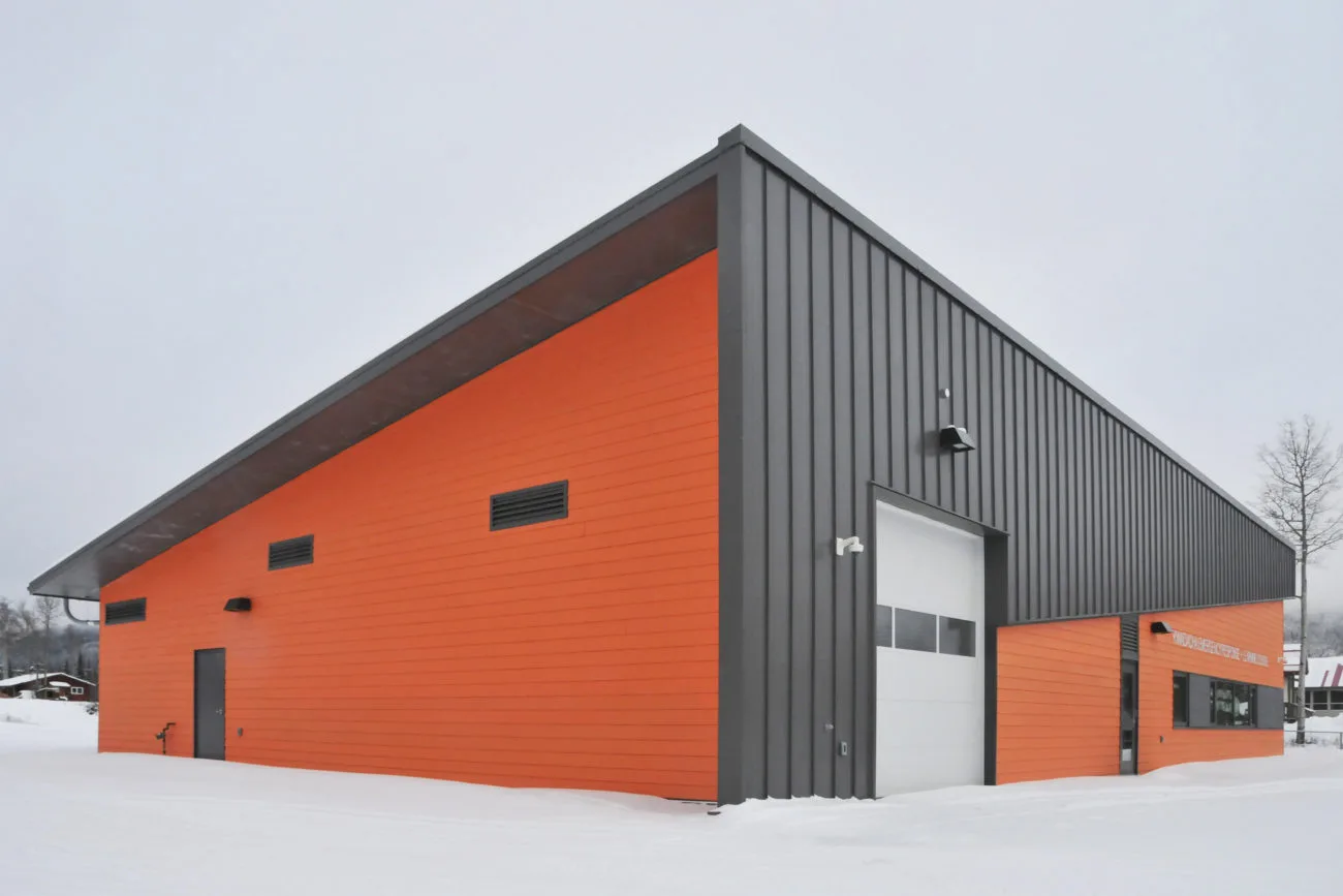 The vehicle bay end of the building, its overhead door facing the cleared apron.